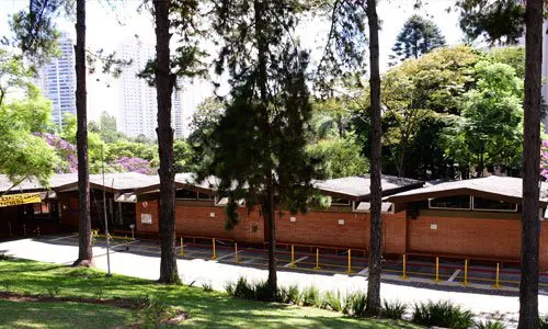 Prédio térreo da Educação Infantil cercado por gramado e árvores altas