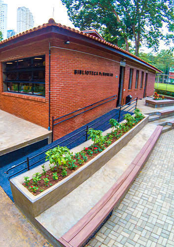 Fachada da Biblioteca Padre Moreau em tijolos, com rampa de acesso e canteiros