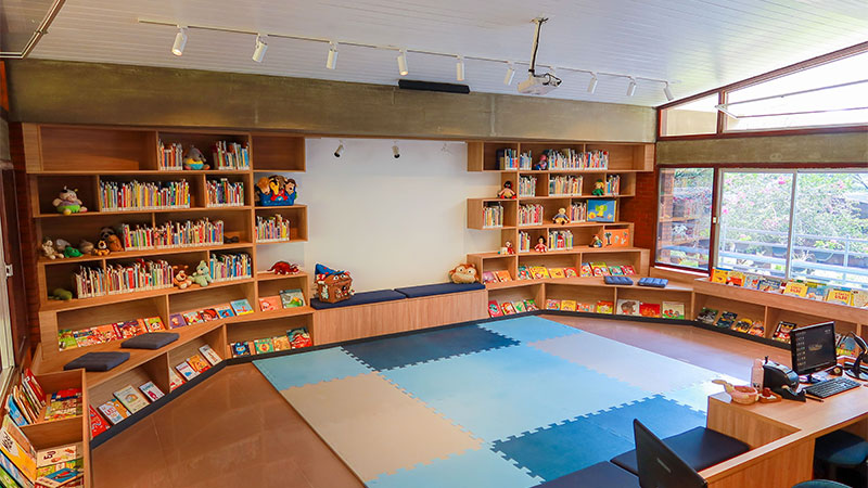 Biblioteca Infantil Santo André Bessette com estantes, livros, brinquedos e tapetes