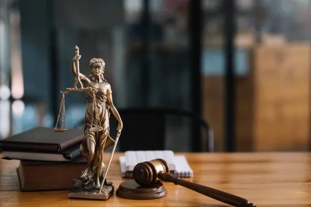 A bronze statue of Lady Justice on a desk beside a gavel