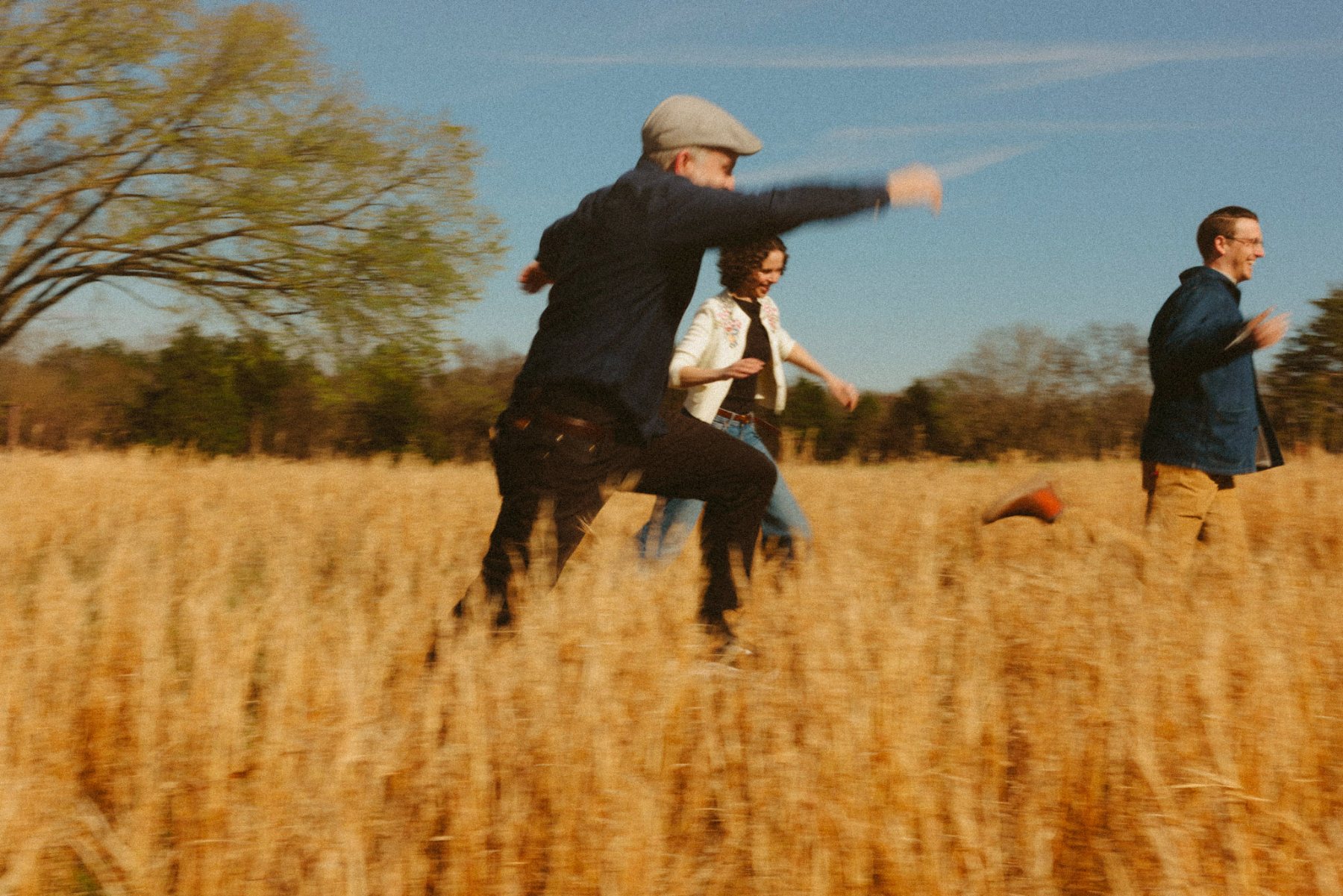 Chris Weldon leaping through tall grass with Alex and Corey