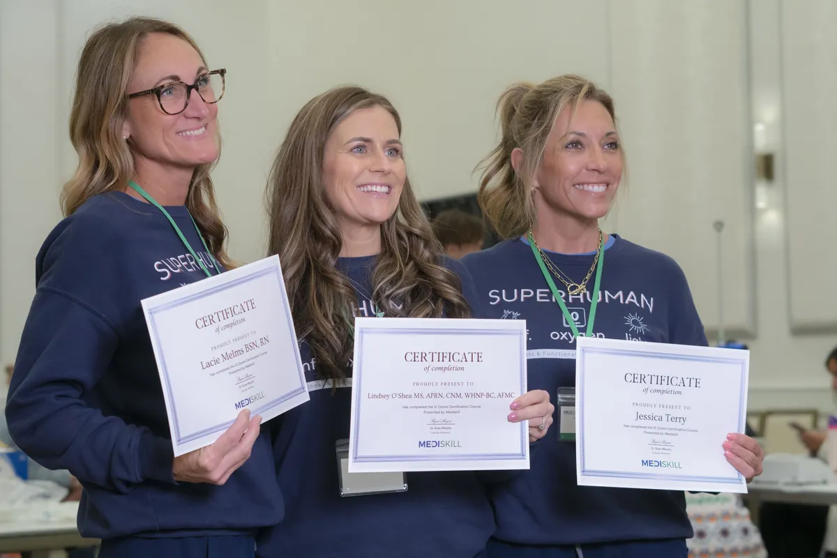 Three smiling graduates hold up their MediSkill certificates of completion
