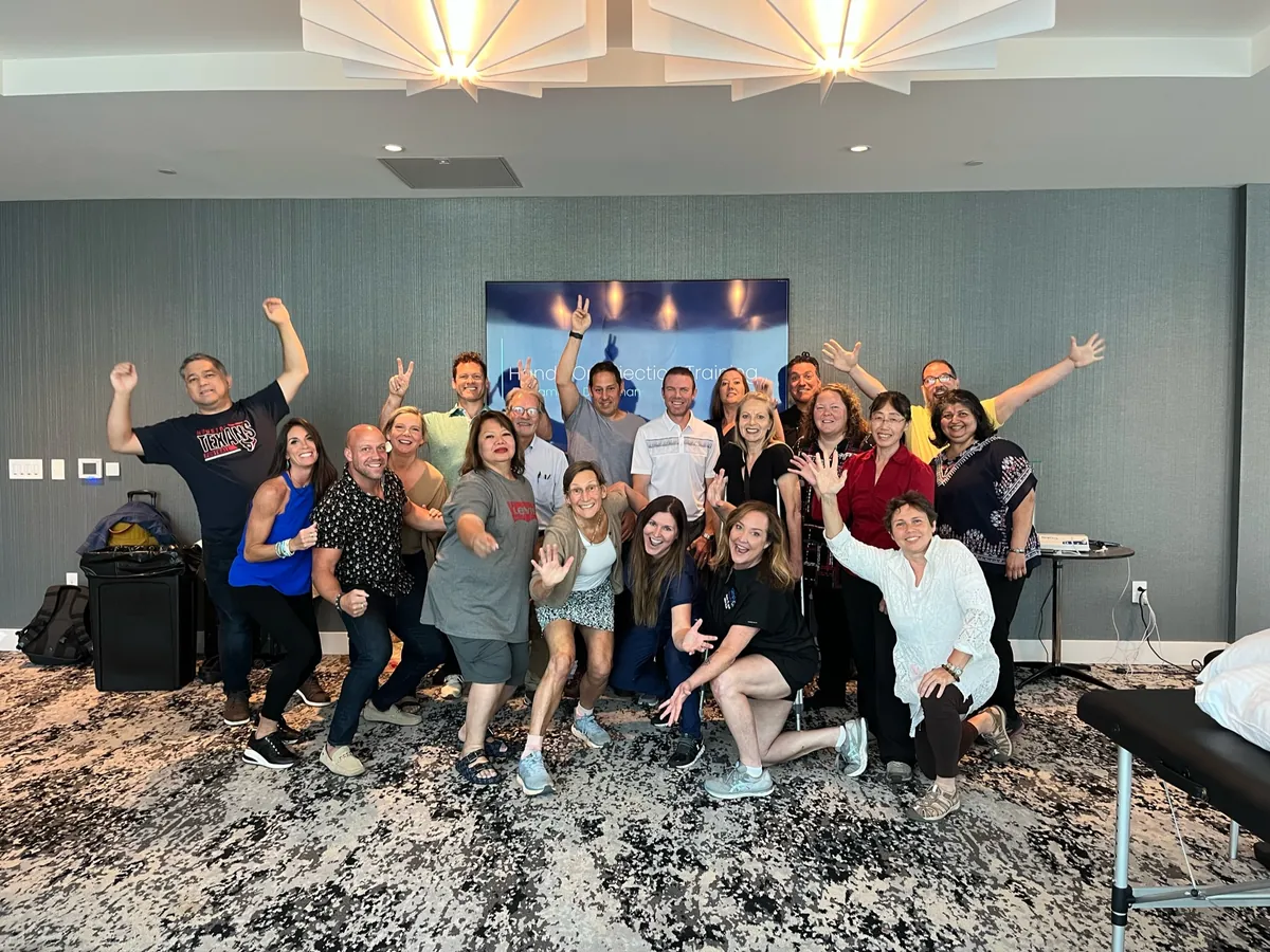 A class celebrates with raised arms on the last day of a live training