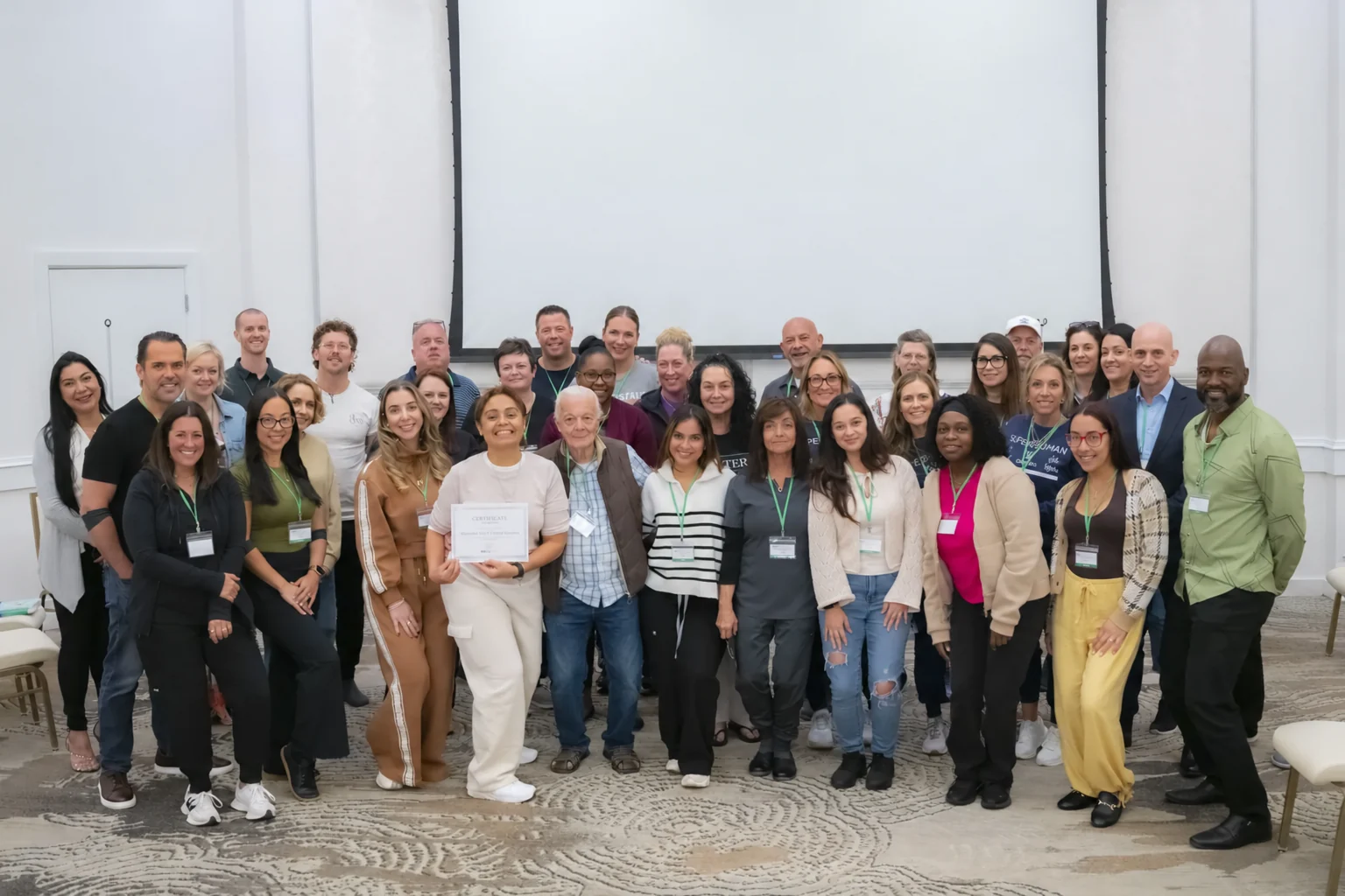 A full class of clinicians stands together for a group photo at a MediSkill live IV ozone training, one holding a certificate