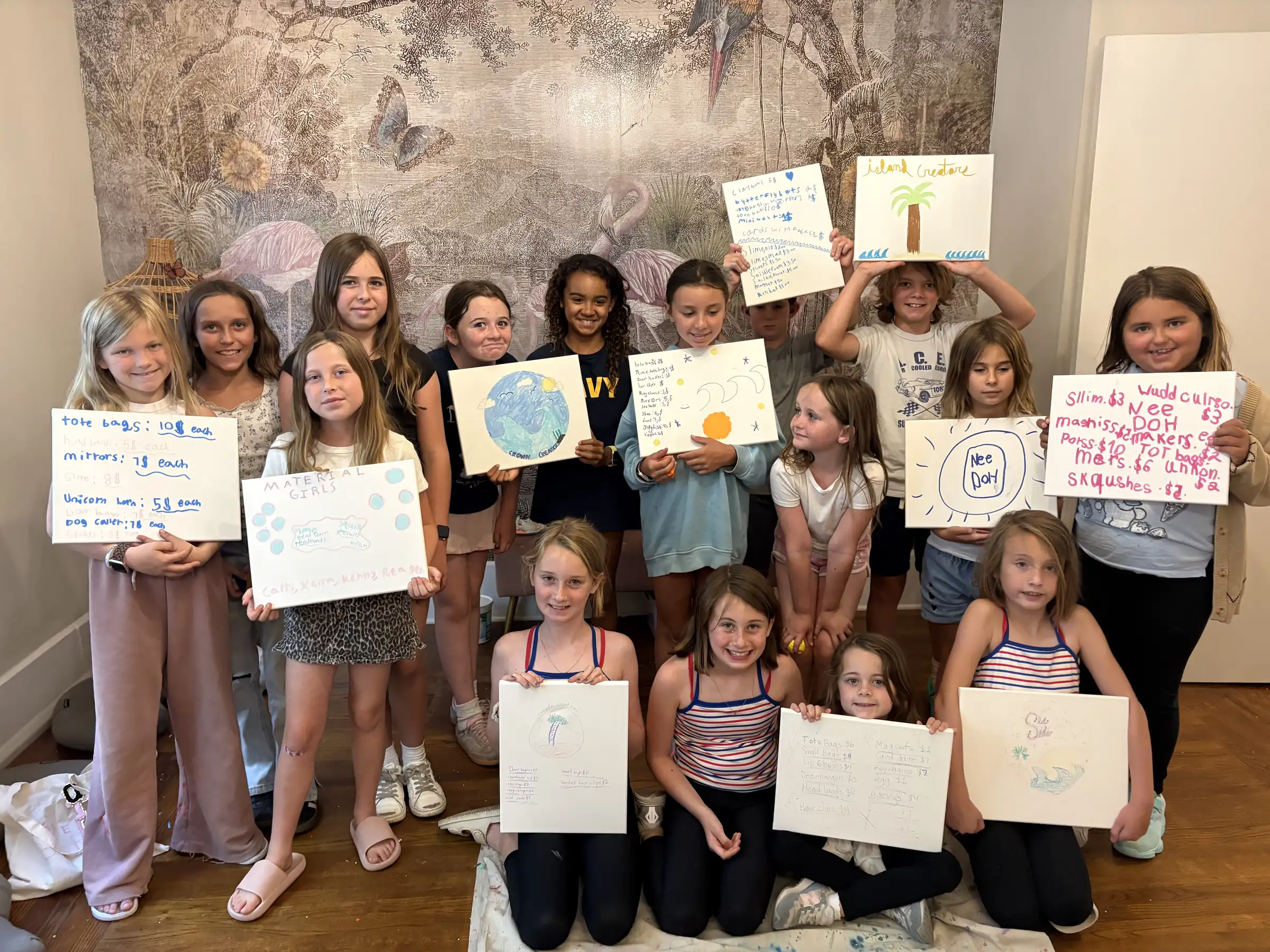 A group of smiling kids in the Monarch Soul studio each holding up a piece of their own artwork