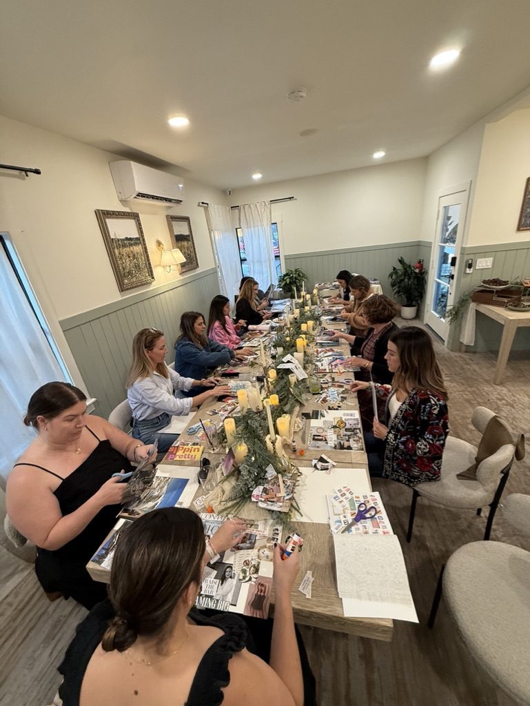 A group seated along a long table making vision boards together in the Monarch Soul studio