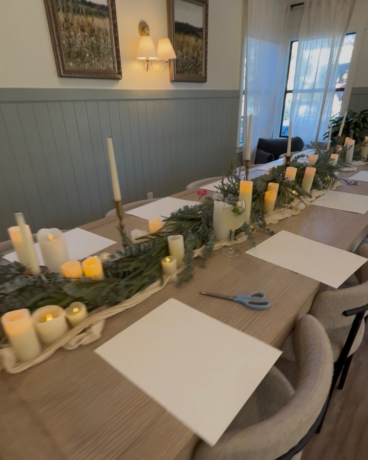 A long table in the Monarch Soul studio set for a private gathering with candles, greenery and paper at every seat