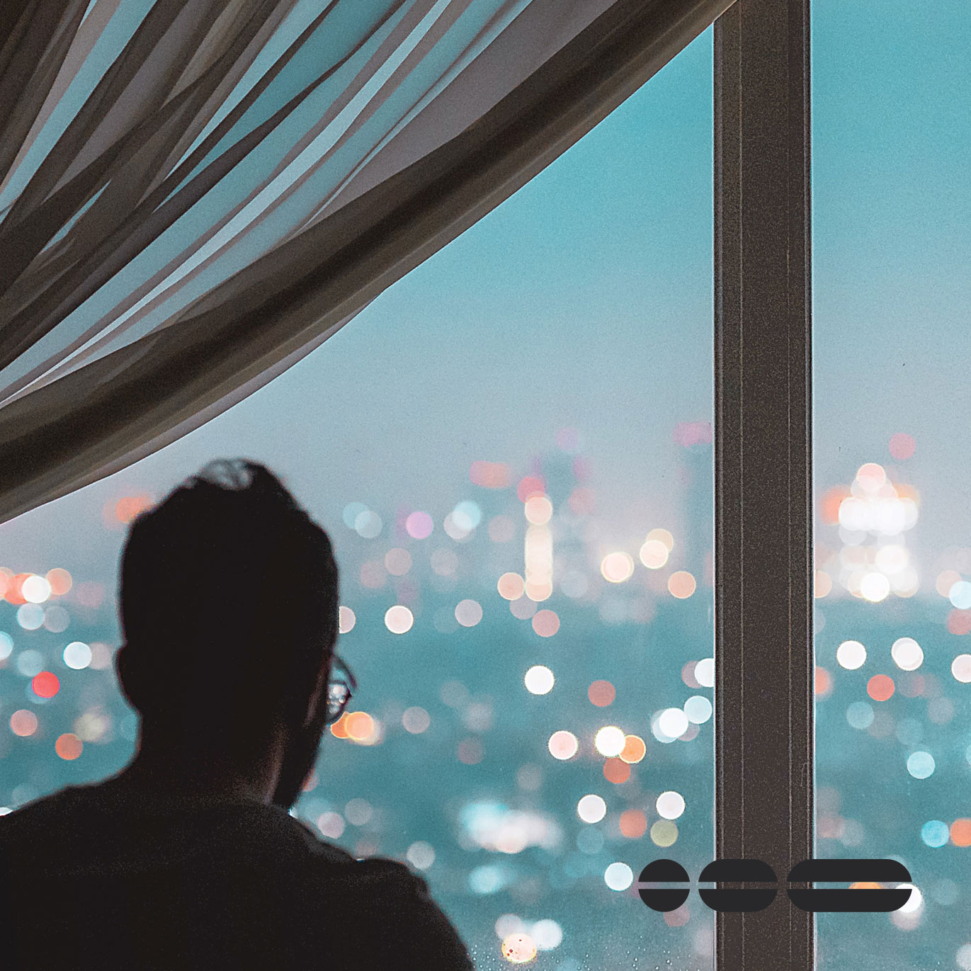 A person looking out the window from a city building which represents professional services. A curtain drapes the left hand side of the image.