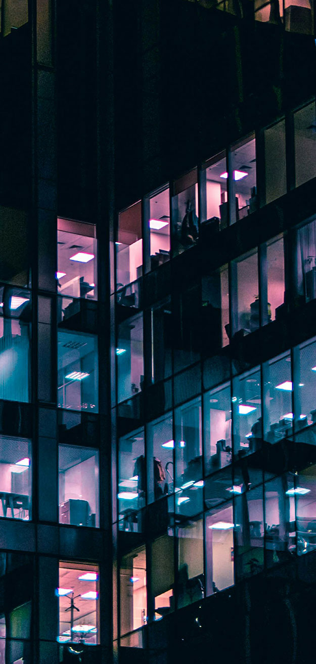 Close up of city building with lights on across four floors.