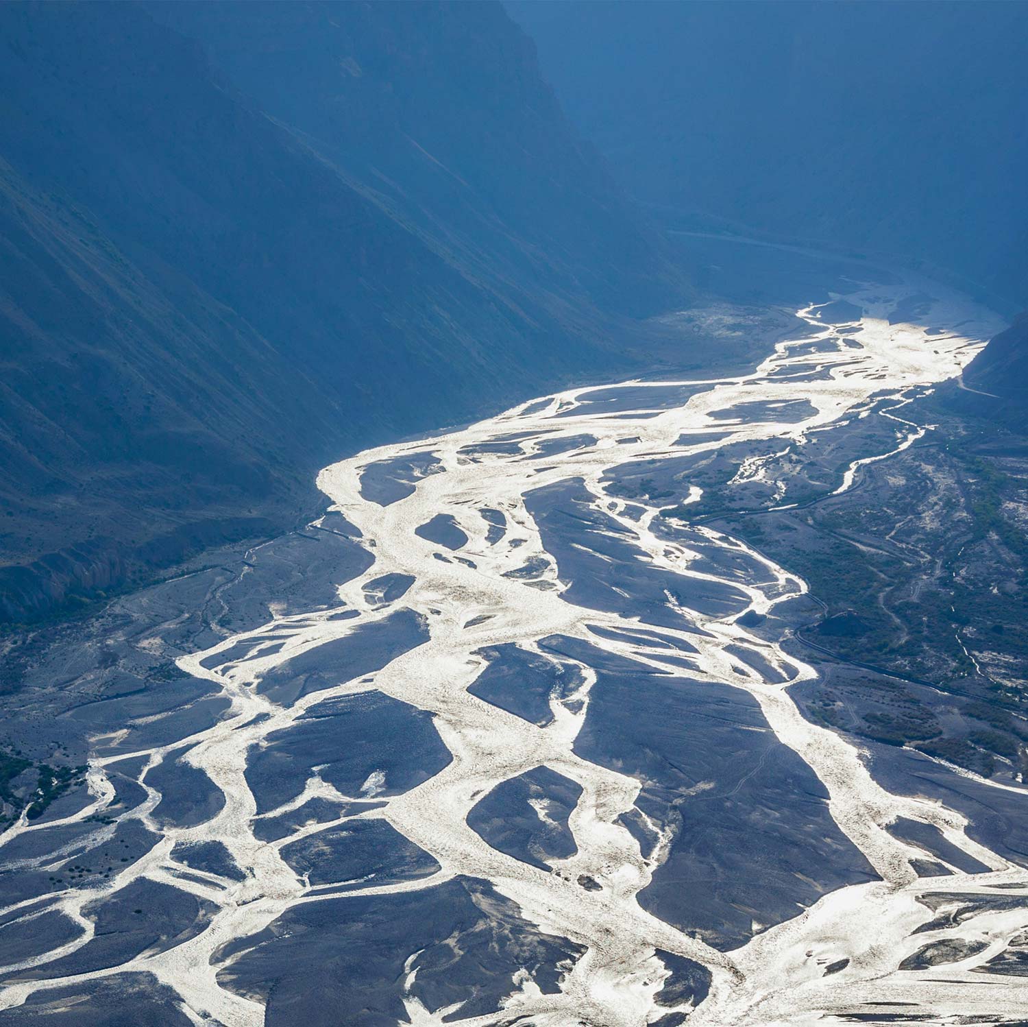 White stream on black riverbed, with black mountains.