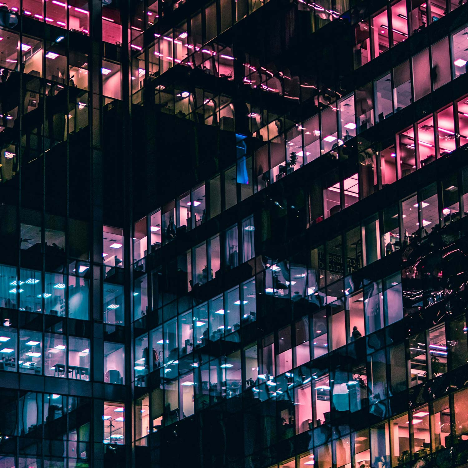 Professional services, corporate building at night, lit up with workers still at work.