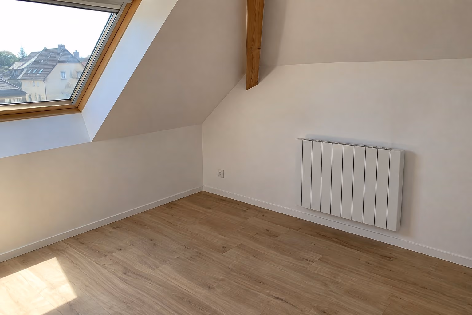 Radiateur électrique fixé au mur d'une pièce sous combles.