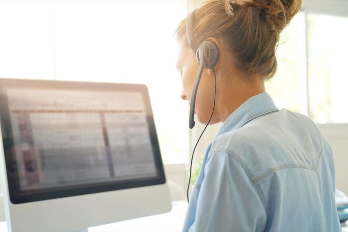 Woman wearing a headset looking at a spreadsheet on a desktop monitor