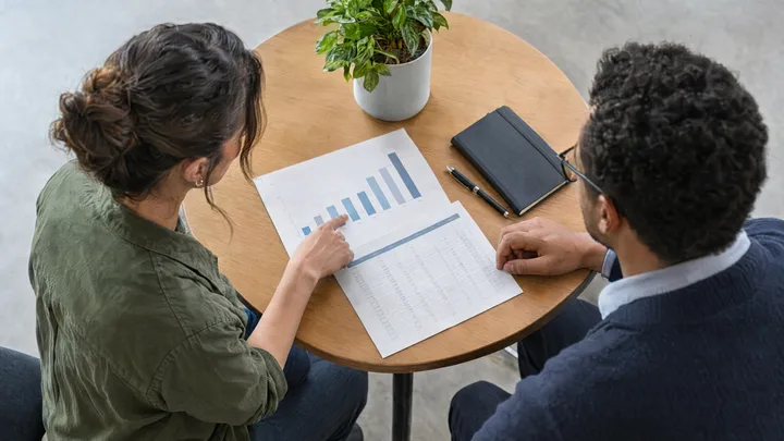 Zwei Personen besprechen eine gedruckte Auswertung mit Balkendiagramm.