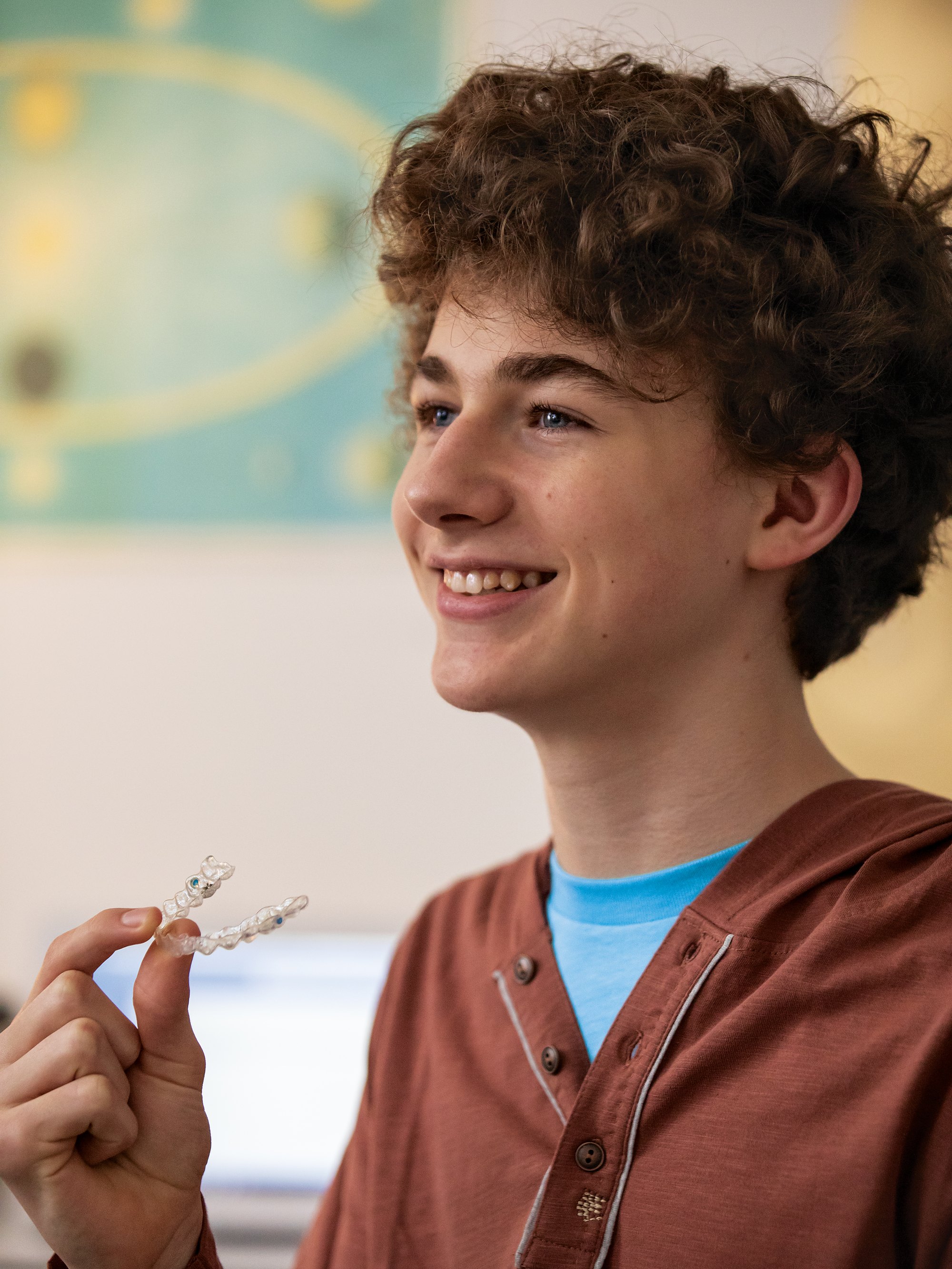 A teenager holding a clear aligner