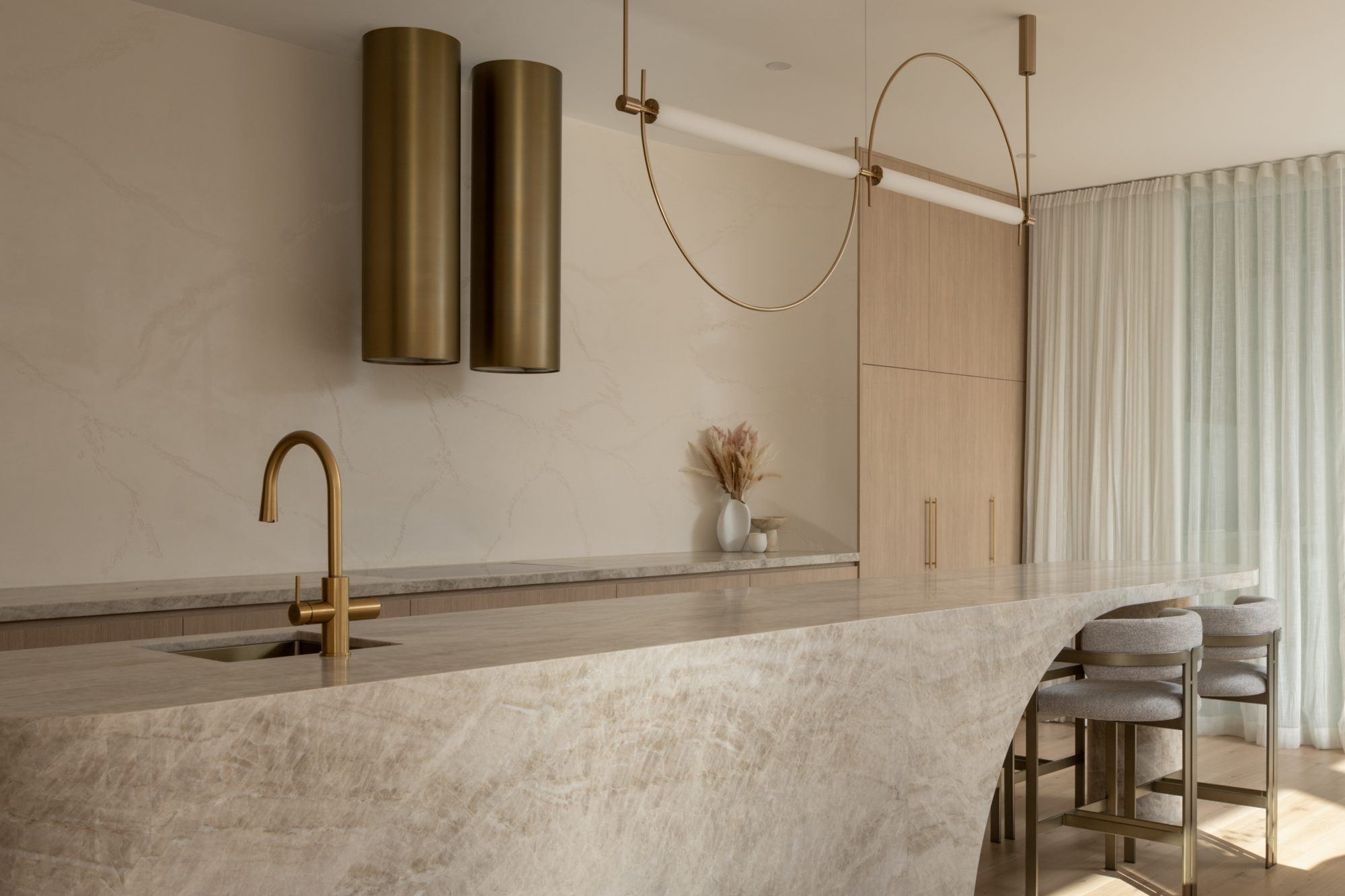 Luxury Sunshine Coast kitchen with a natural stone island benchtop and brass pendant lights