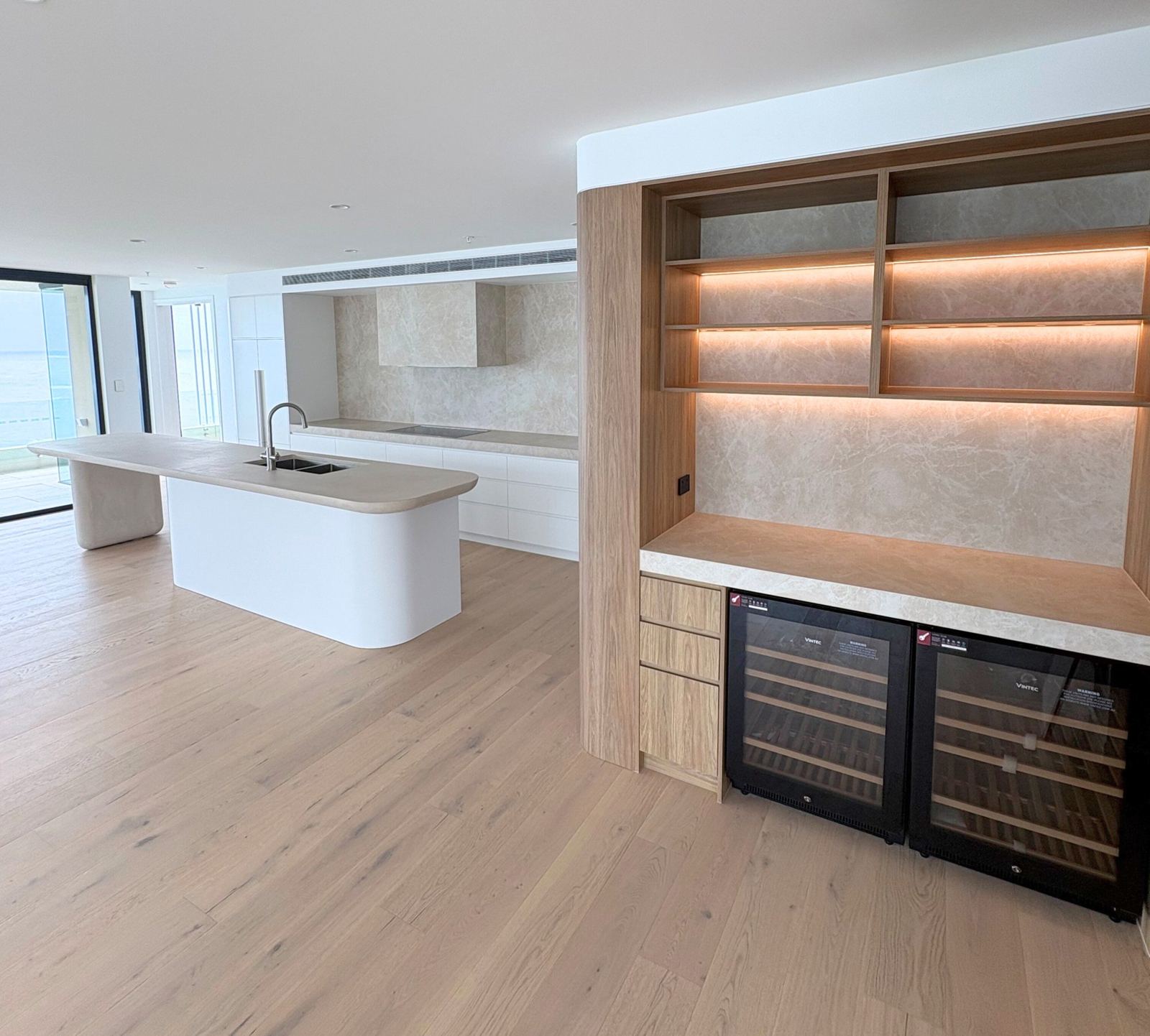 Kitchen with stone benchtops and backlit timber shelving