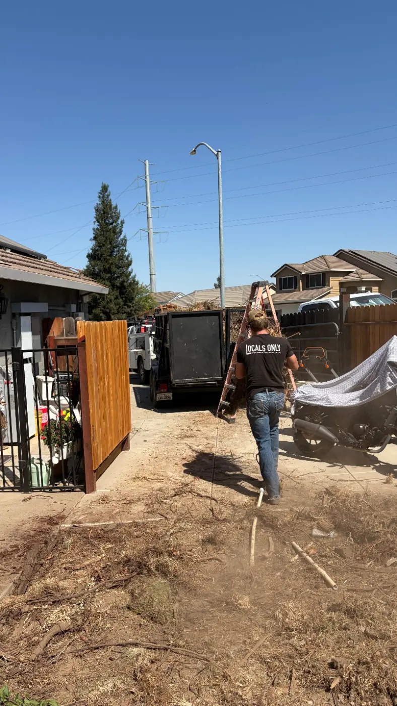 Crew member carrying yard debris down a driveway to the Jake's Junk Away trailer