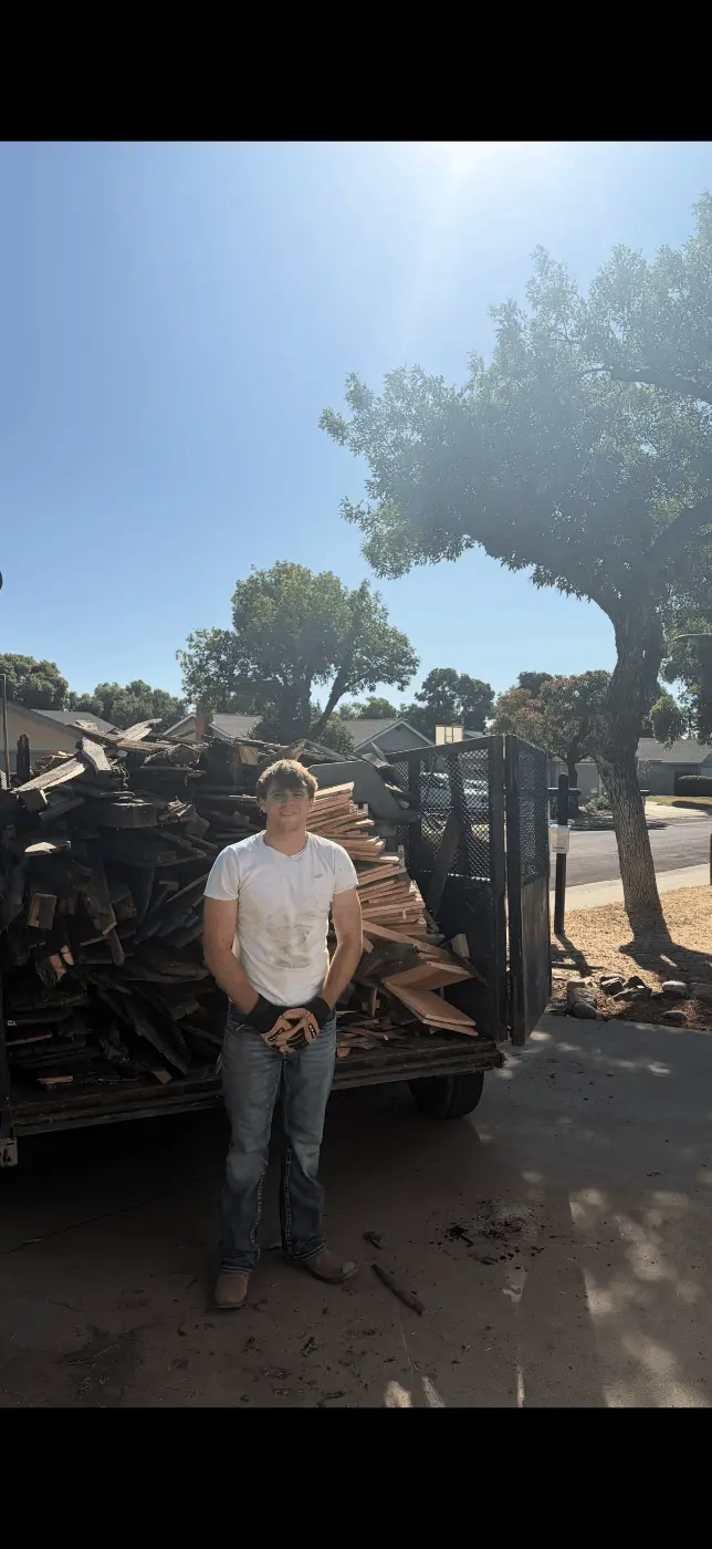 Crew member in front of a trailer loaded with old wood and fence boards