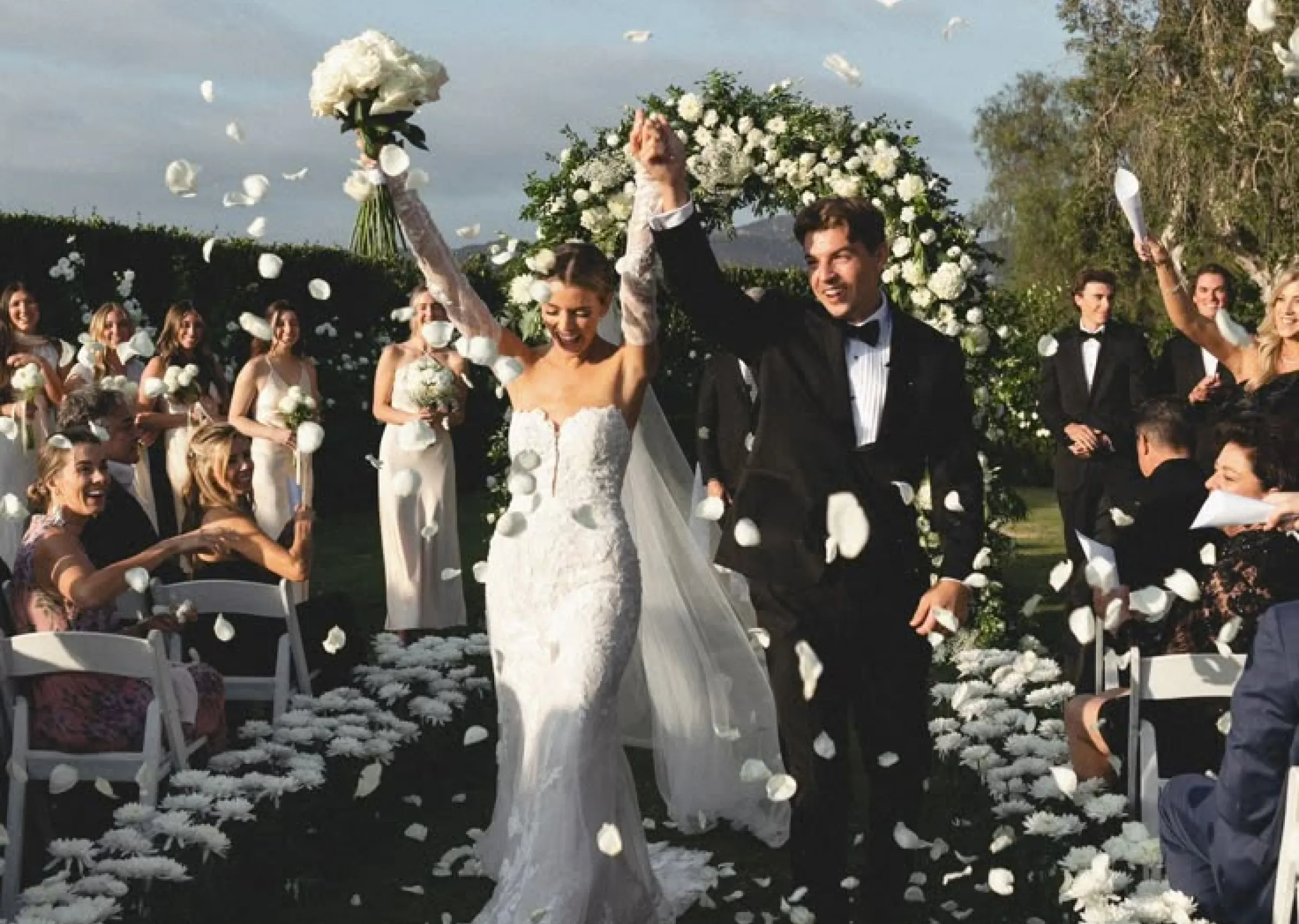 Newlyweds walking down the aisle under falling petals
