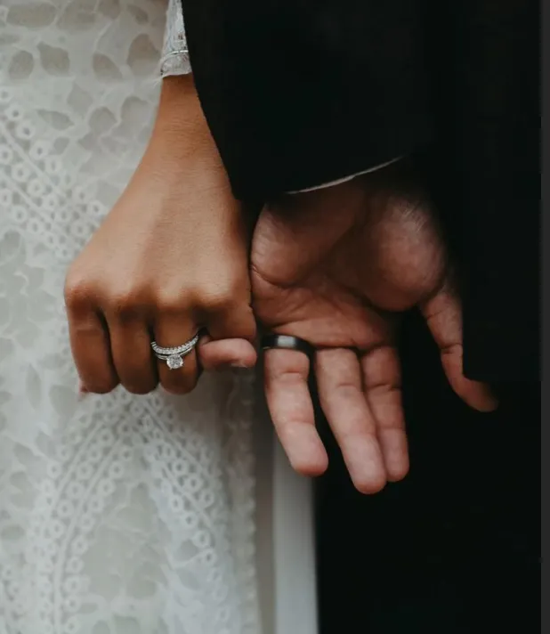 Couple holding hands, wedding ring detail