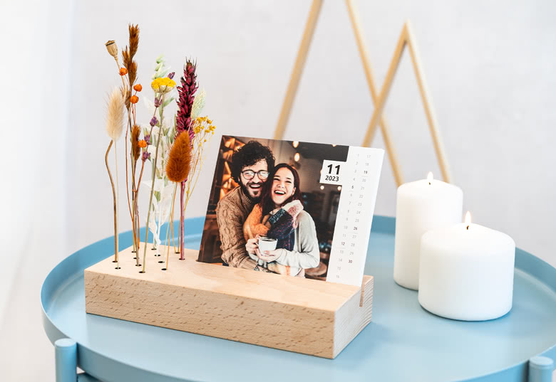 Tischkalender im Holzaufsteller mit Trockenblumen und Fotos