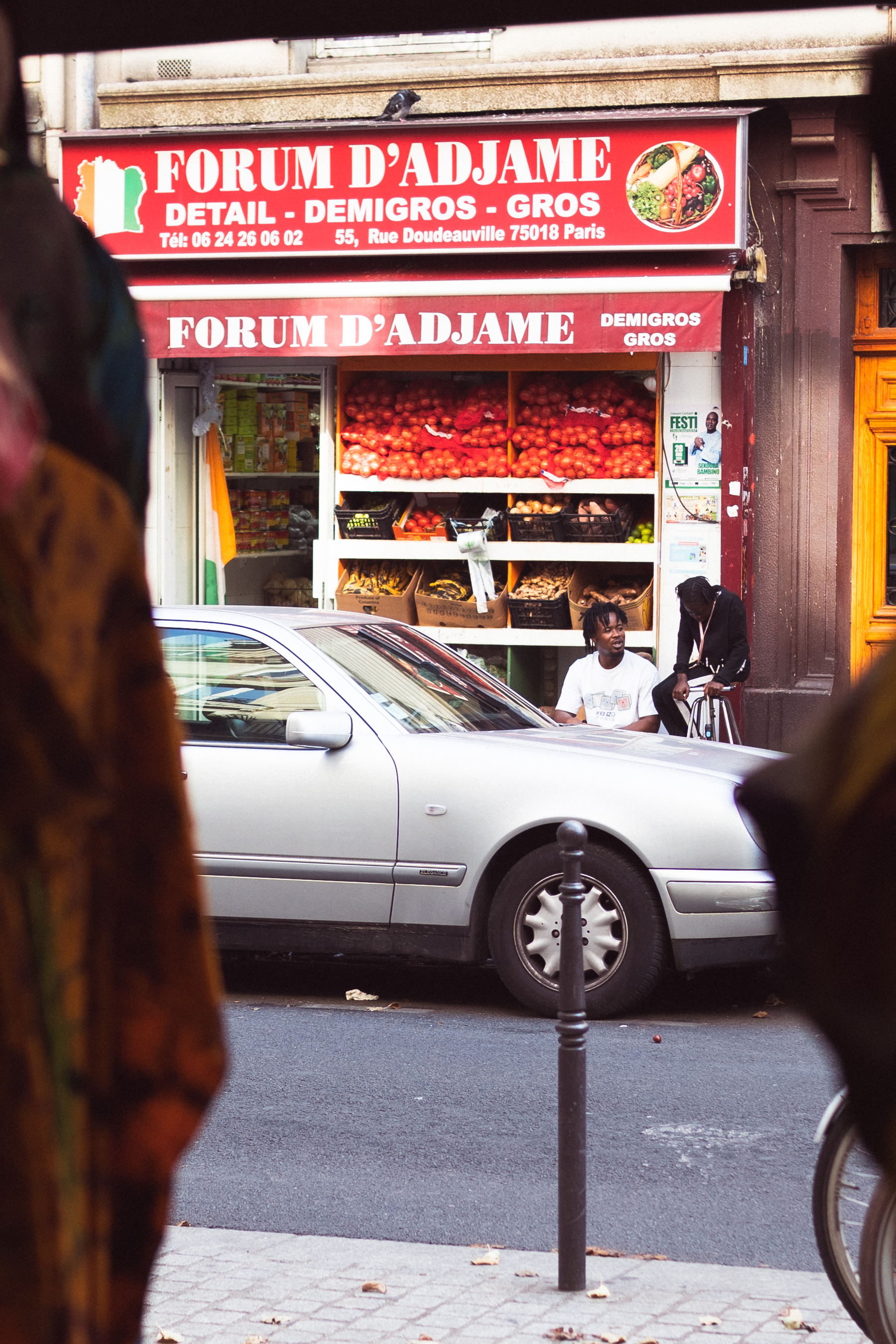 Forum d’Adjamé African grocery storefront in Paris, framed by the foreground with people outside