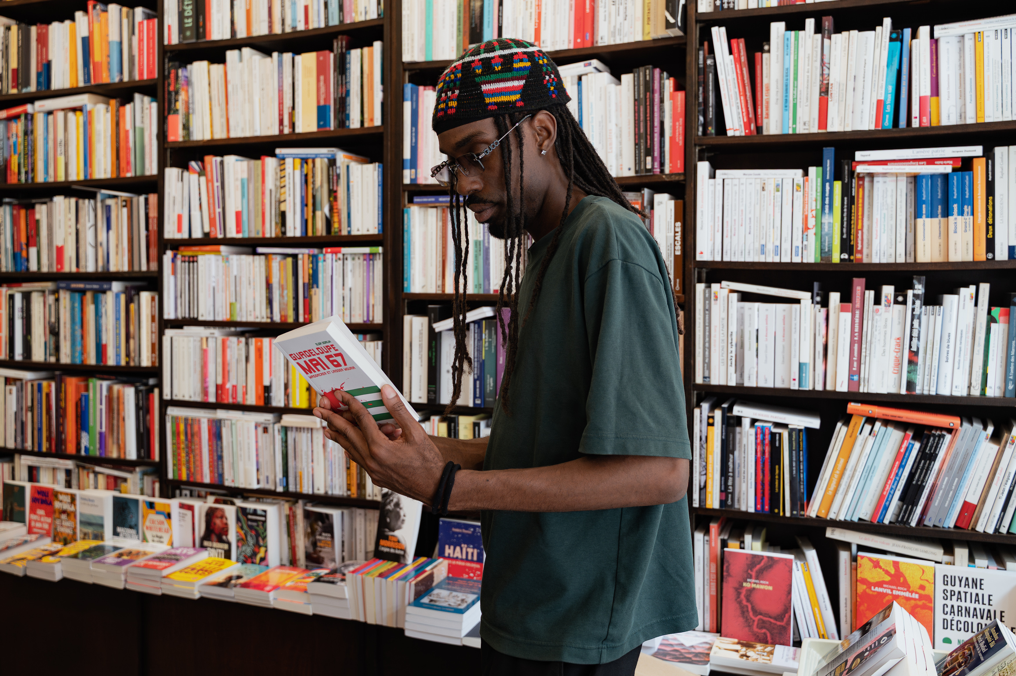 Man reading Guadeloupe Mai 67 in a bookstore