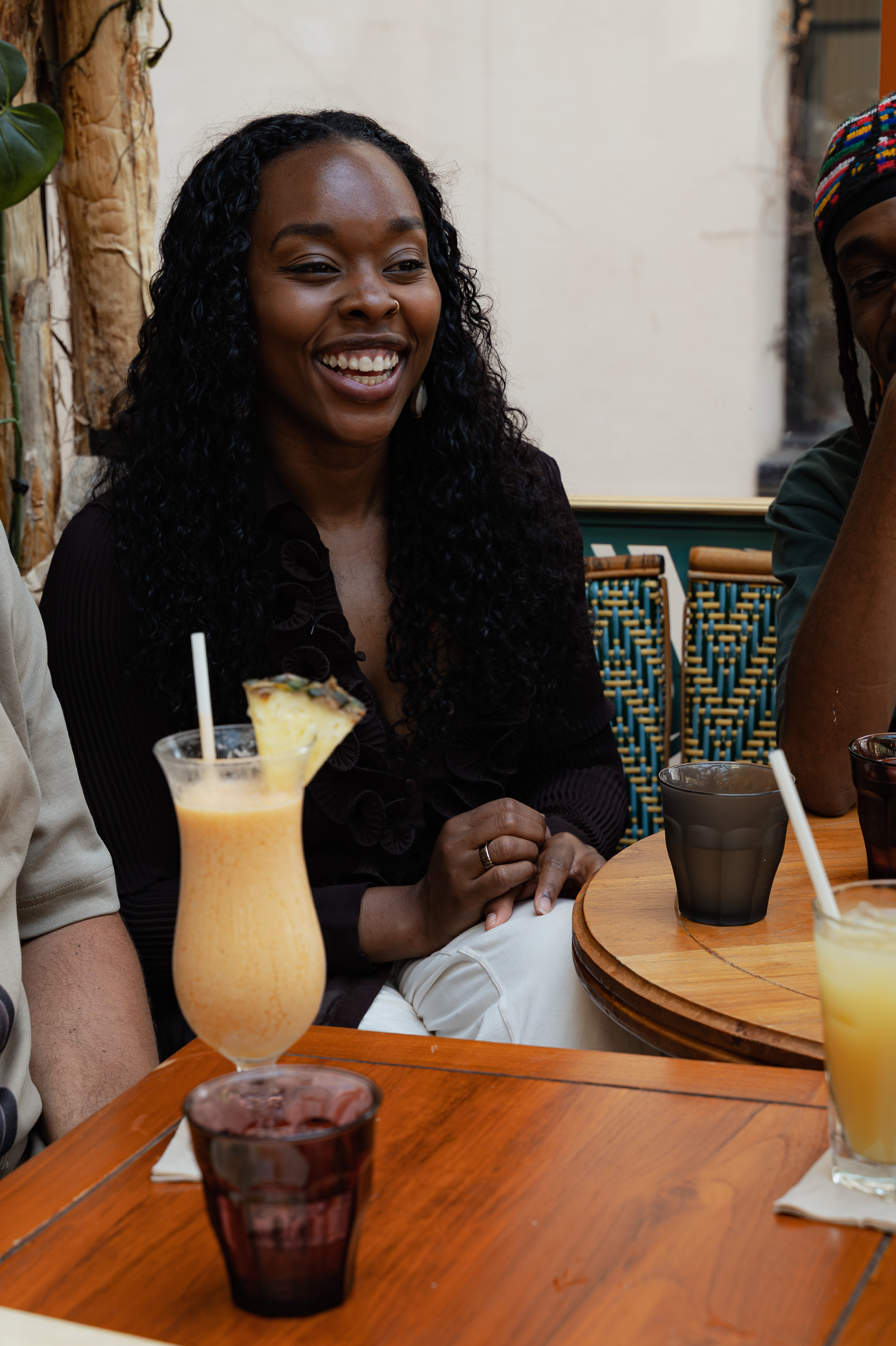 Woman smiling at a restaurant table during the AfroNomadik photoshoot