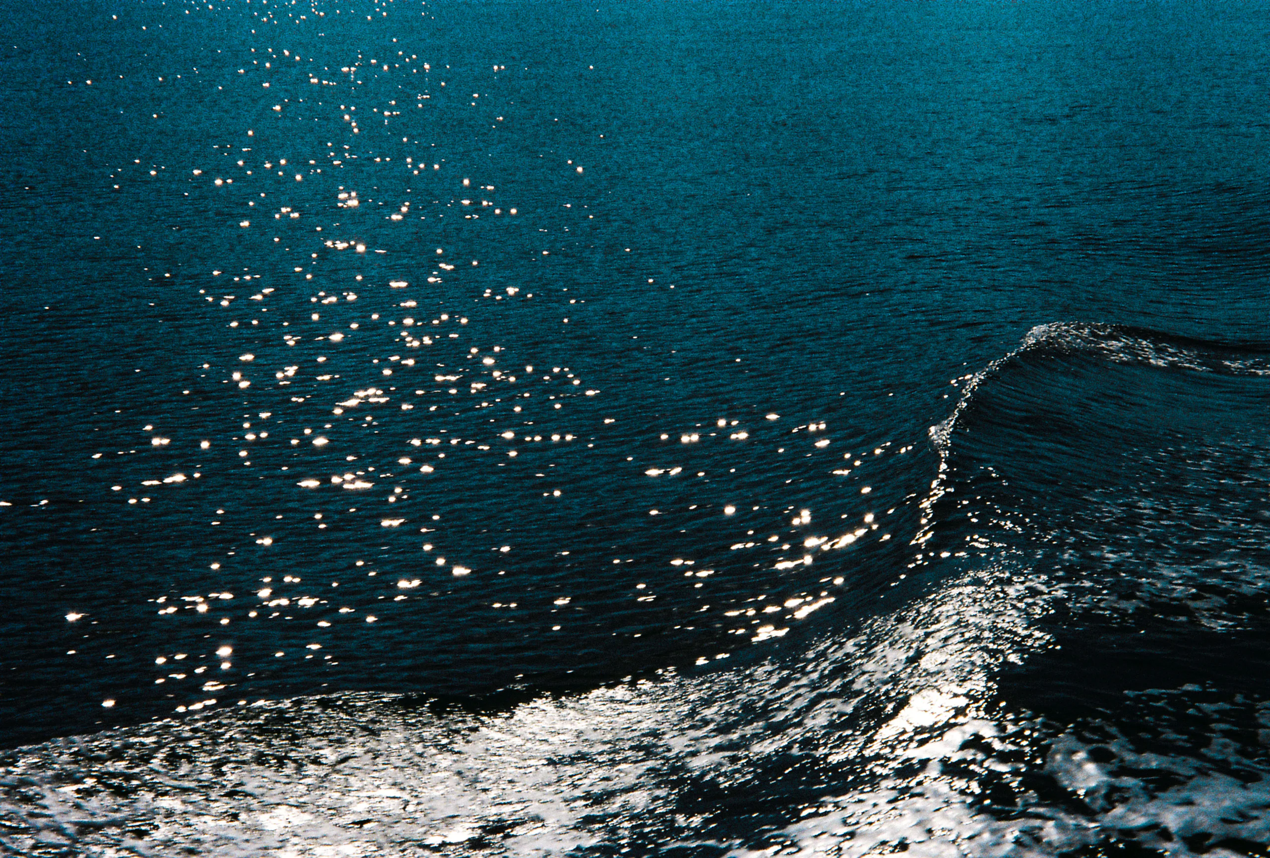 Reflets de soleil sur l'eau sombre, sillage d'un bateau