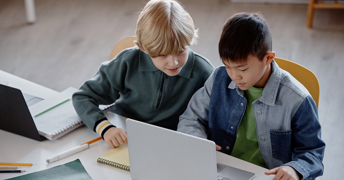 Two students working together on laptops in a classroom
