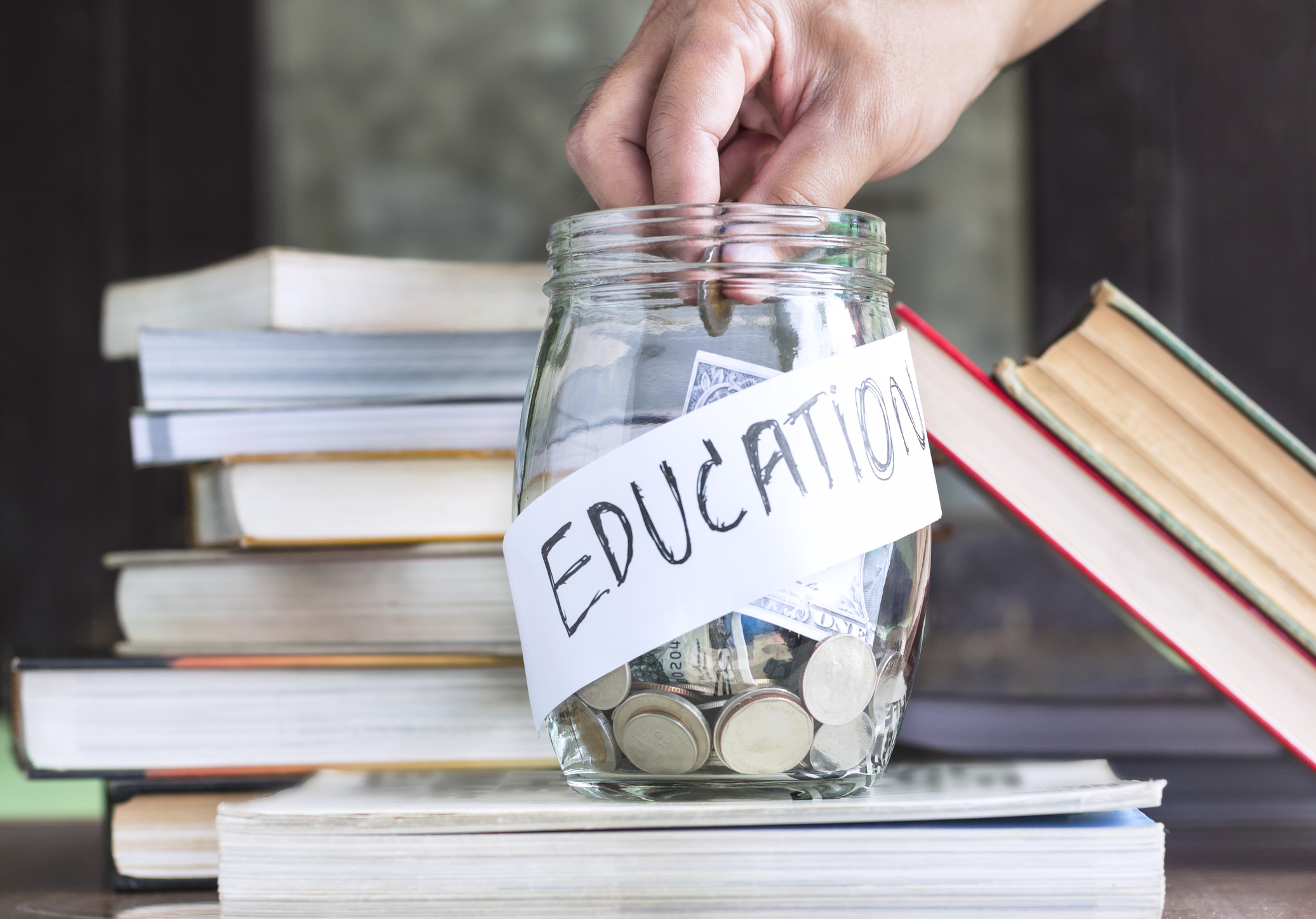 A jar of coins labeled Education on a stack of books