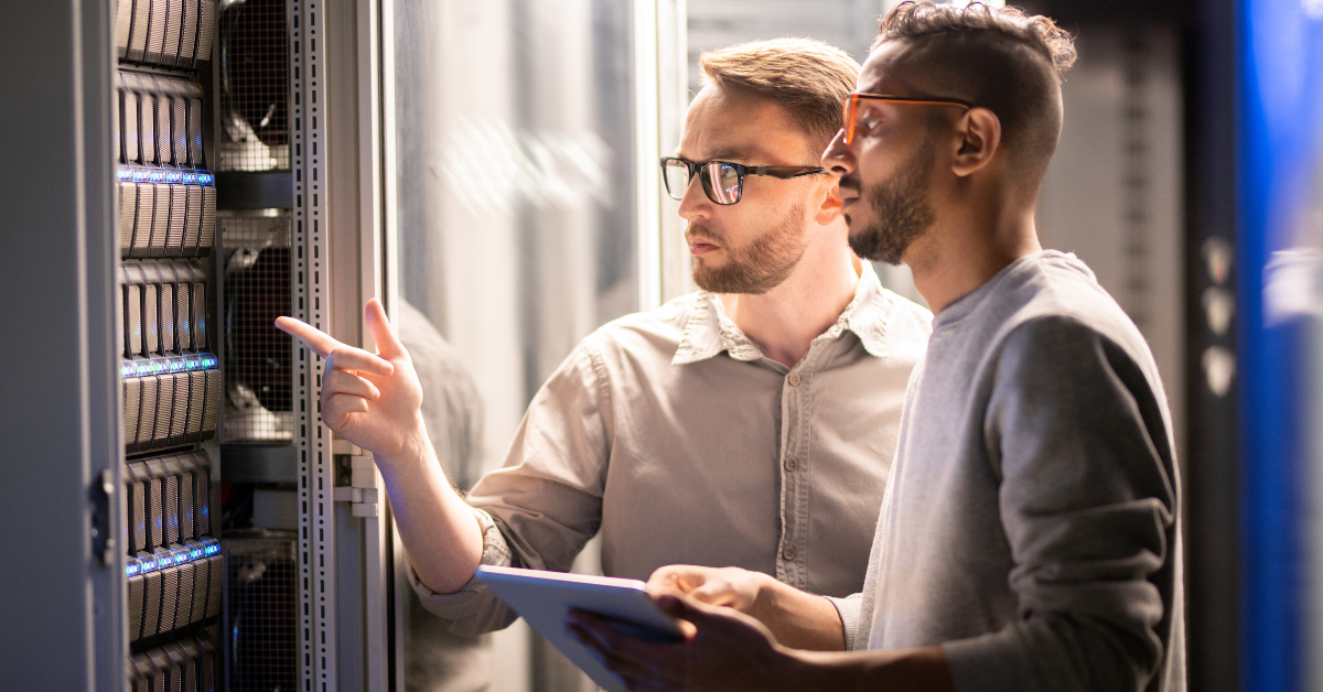 Two IT technicians reviewing a server rack together with a tablet