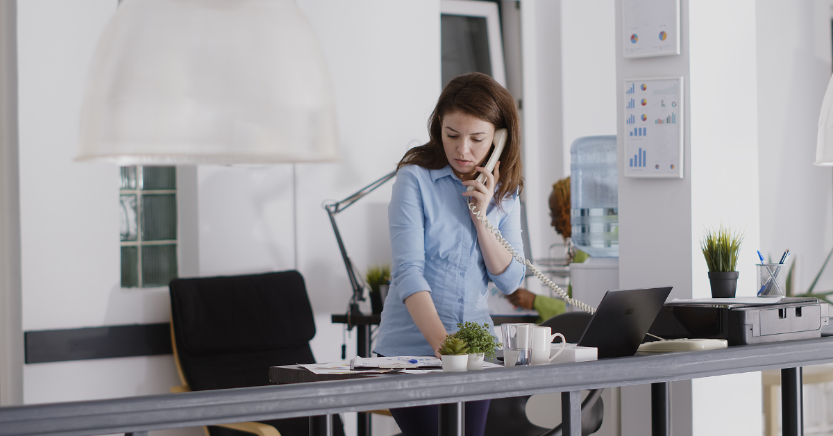 A staff member answering a desk phone in a bright office