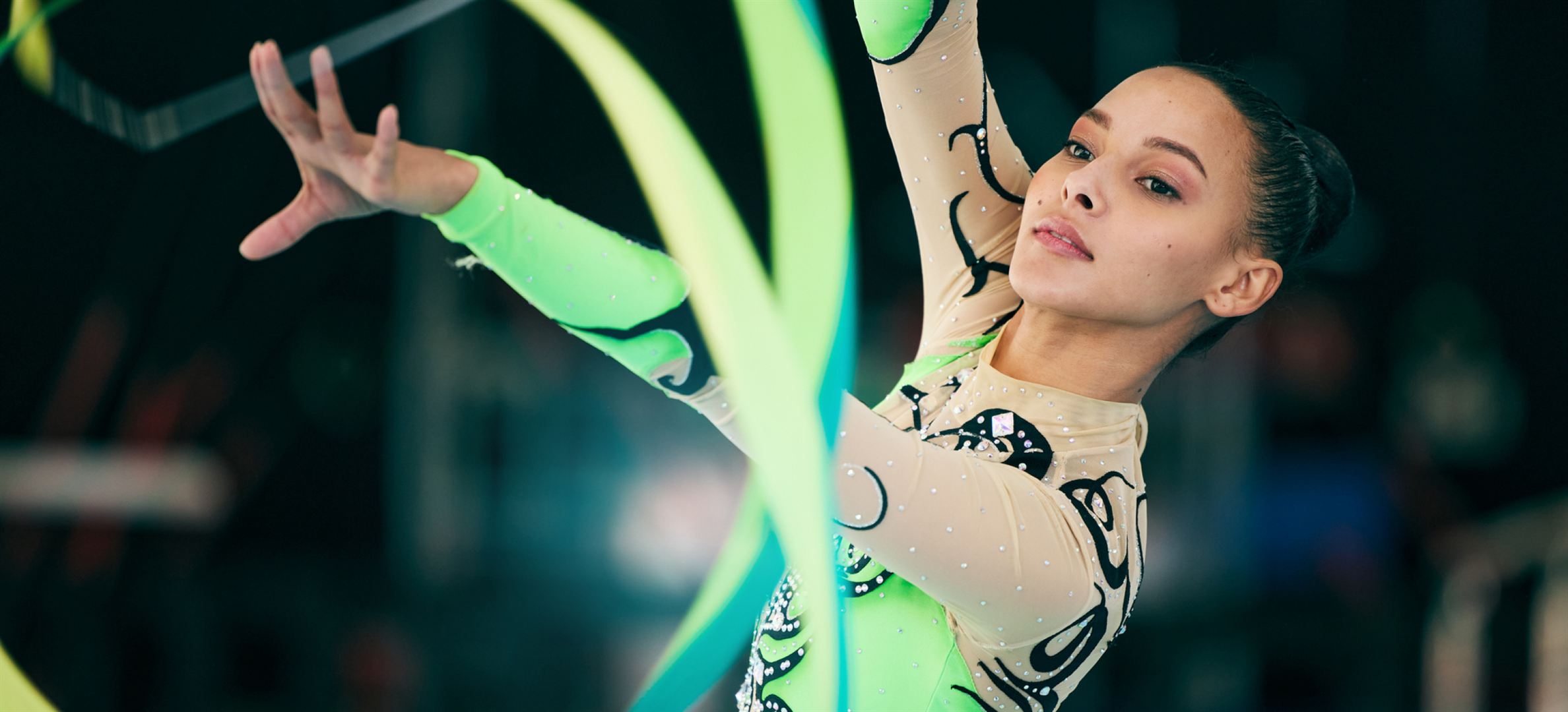 Rhythmic gymnast performing with a bright green ribbon