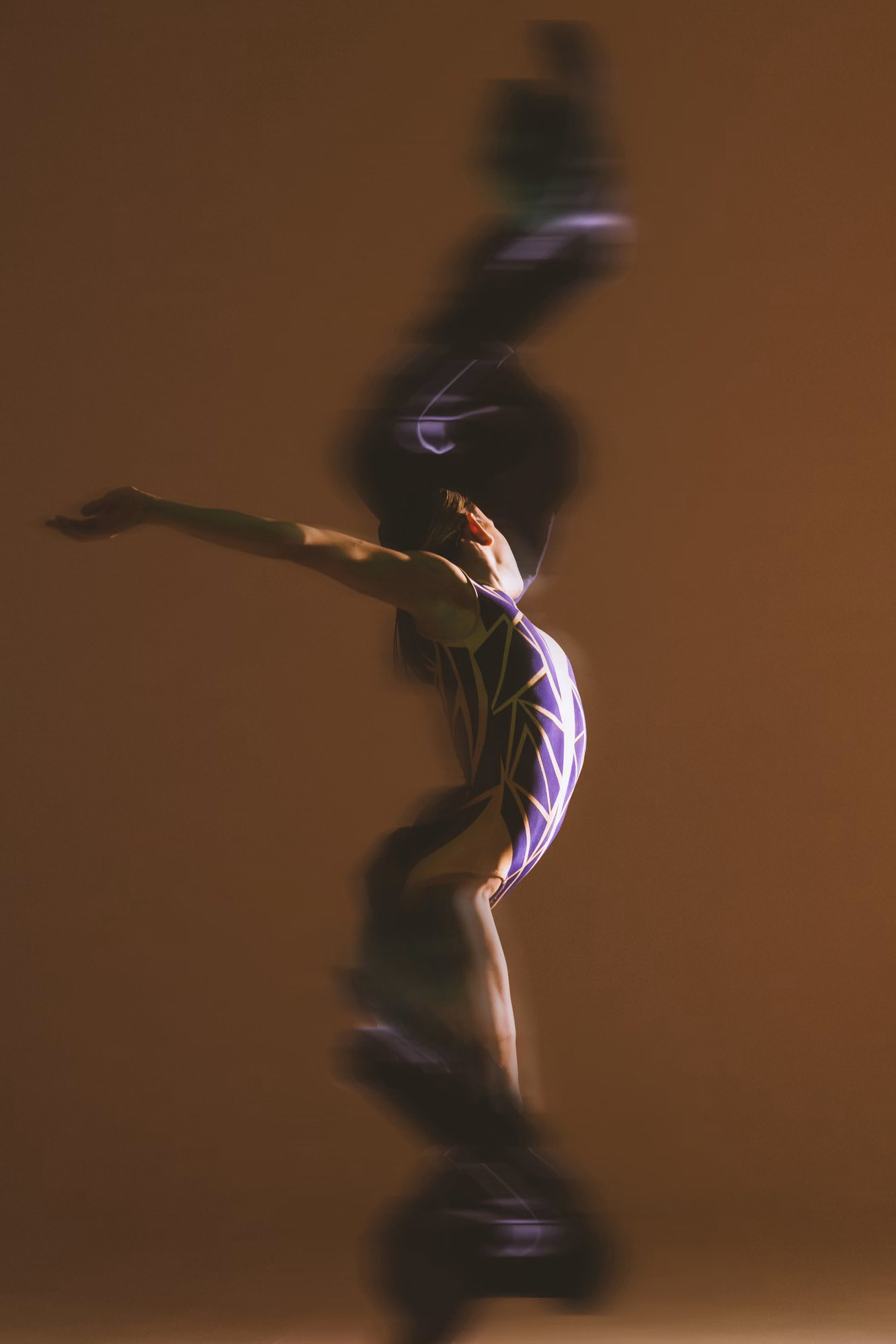 A gymnast mid-flight, captured with a long exposure on a warm brown background