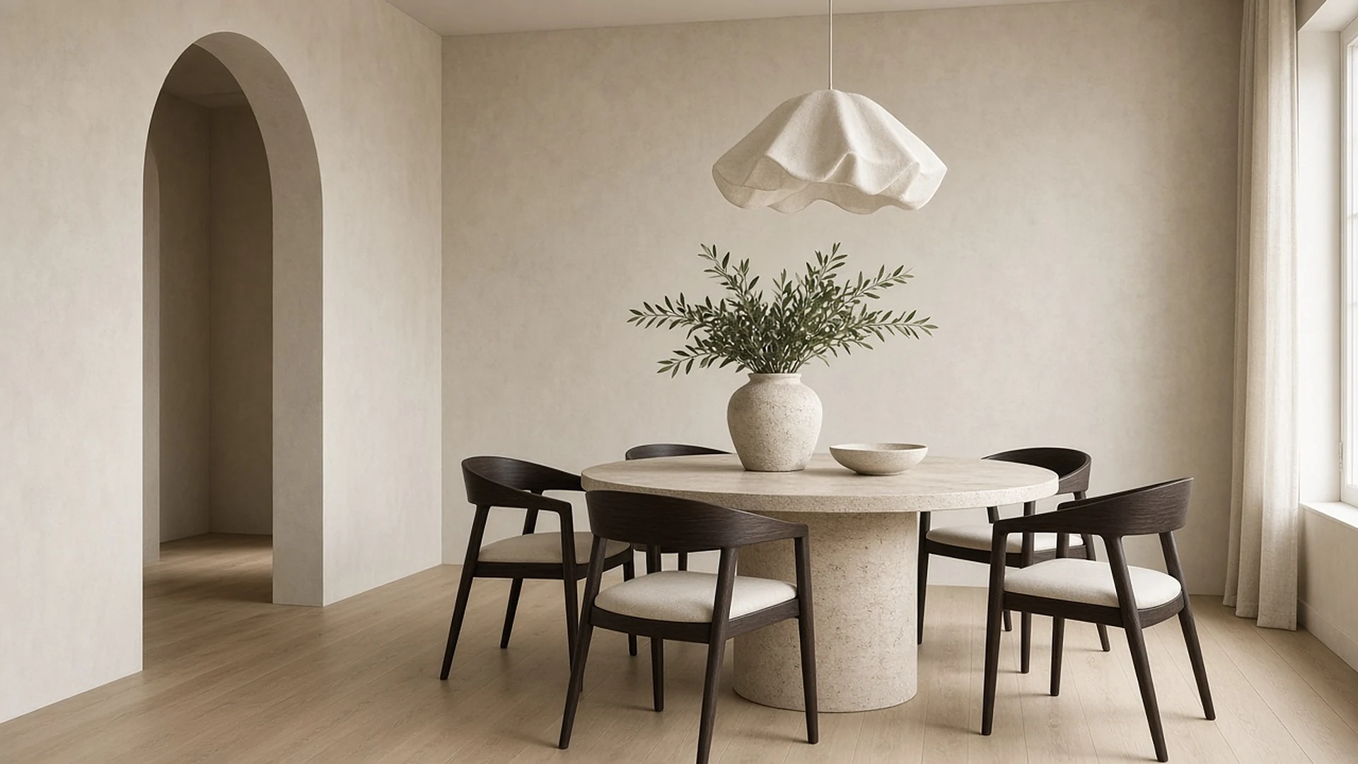 Finished dining room with limewash walls, an arched doorway and a round travertine table