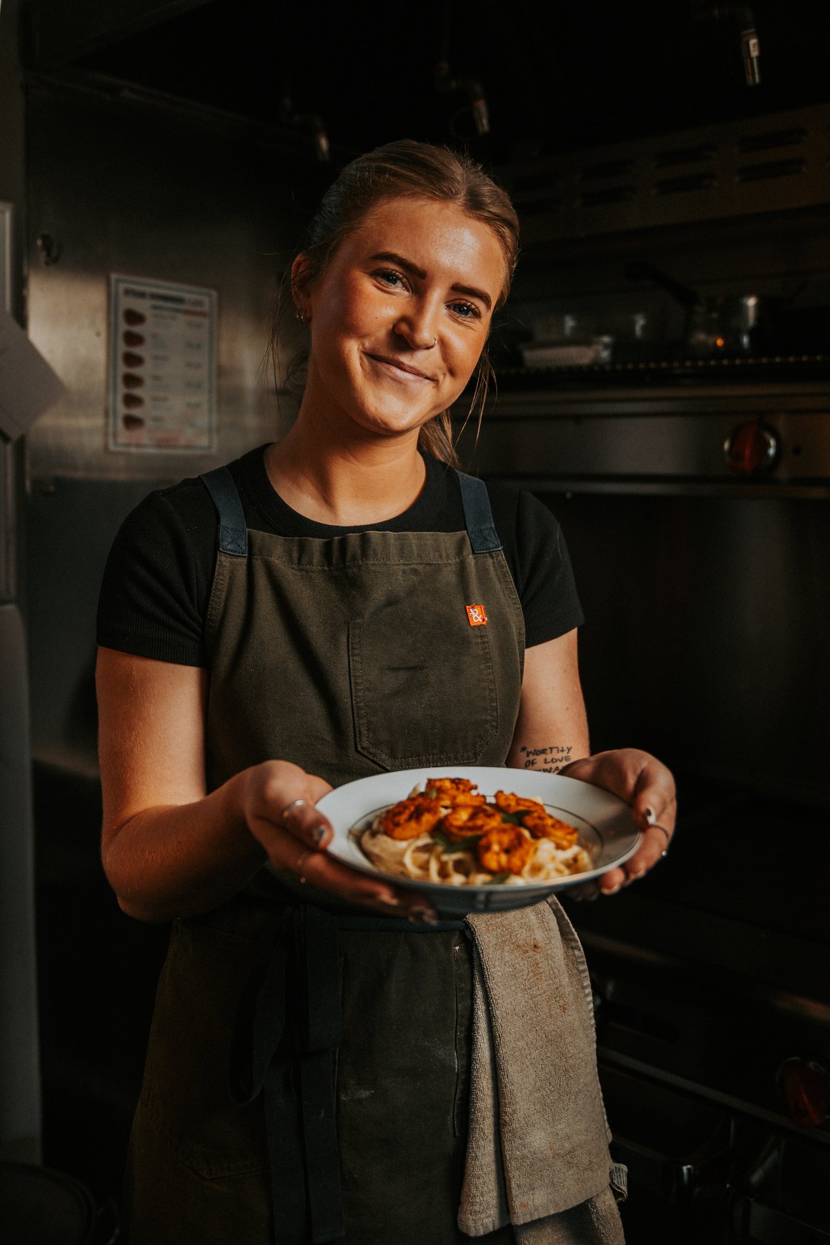 Chef holding a plate of shrimp alfredo