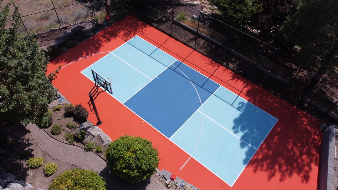 Blue backyard court with contrasting red perimeter and basketball hoop