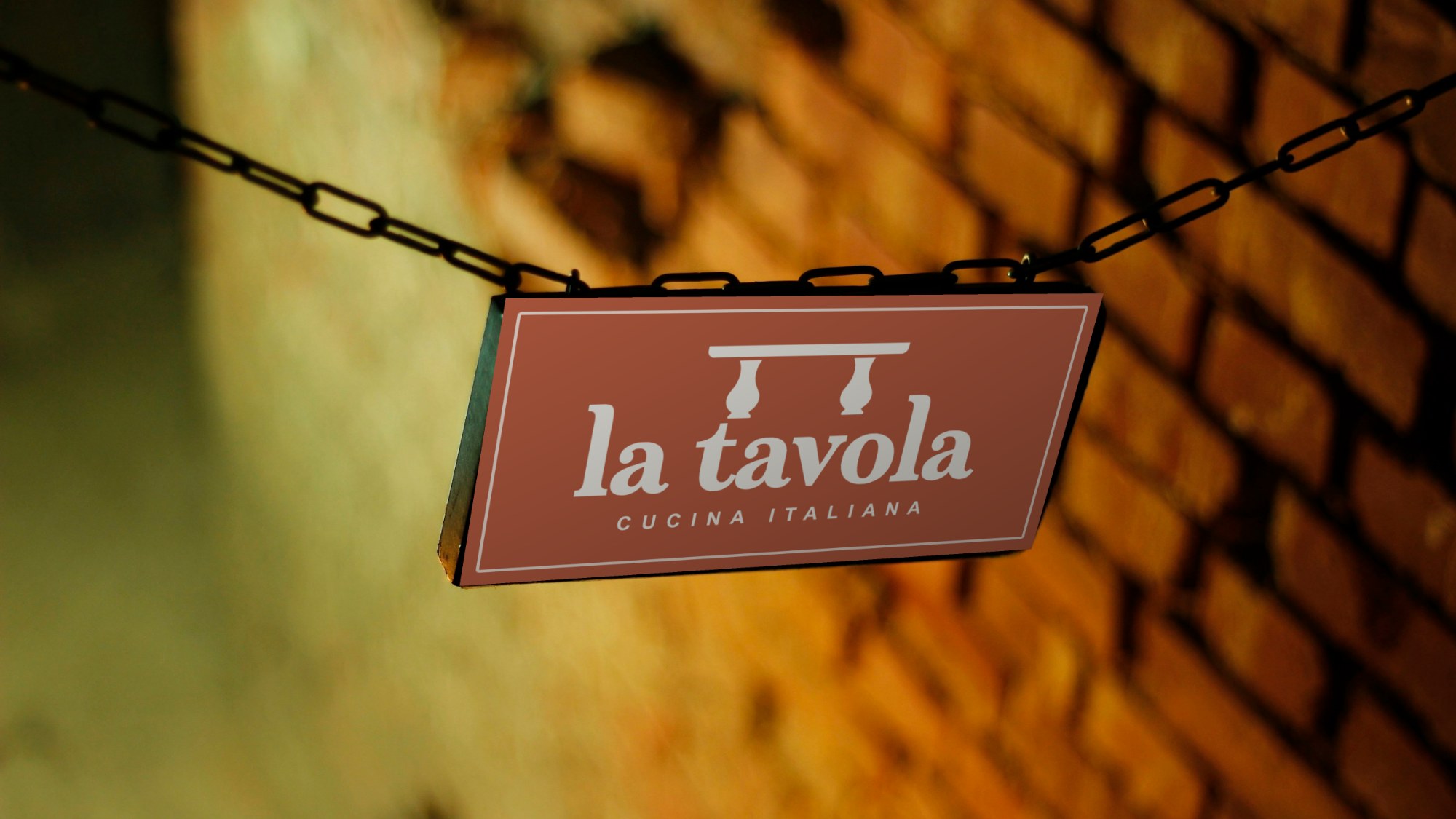 Terracotta La Tavola sign hanging on chains in front of a brick wall