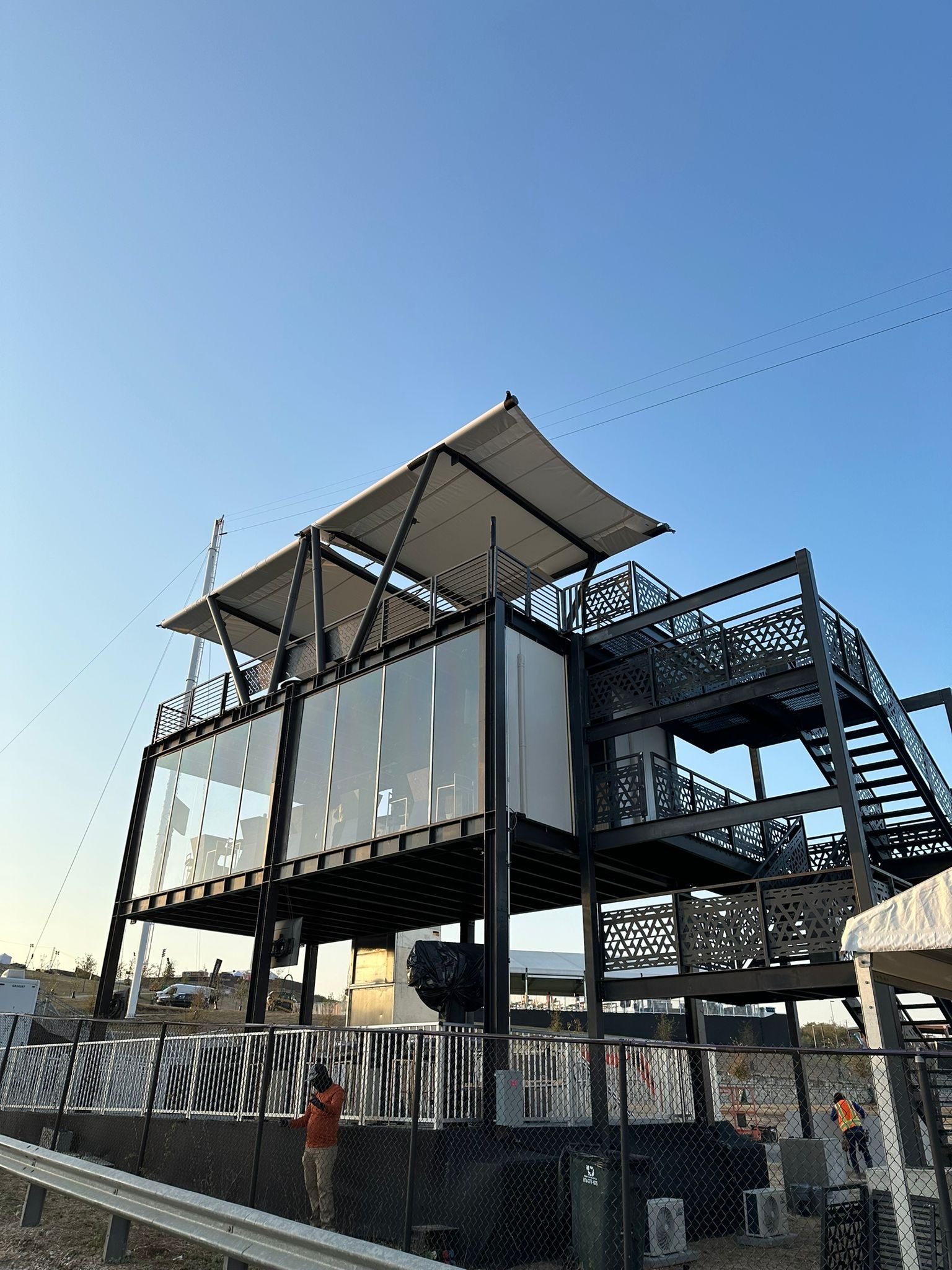 Two-level hospitality module with a rooftop deck and canopy at Circuit of the Americas, Austin, at sunset