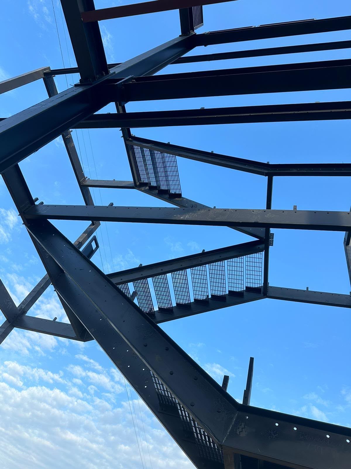 Beams, stair stringers and grating treads seen from below against the sky