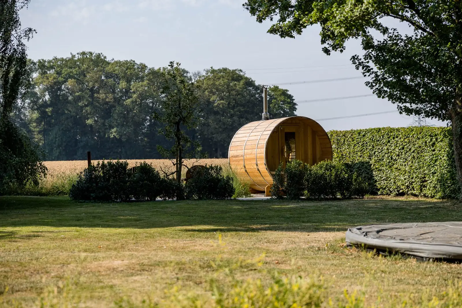 Barrelsauna achter in de tuin aan het graanveld, gezien over het gazon in Enschede