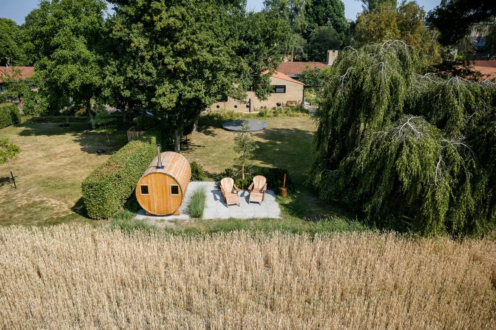 Barrelsauna met terras, houten ligstoelen en cortenstalen houtkachel in Enschede