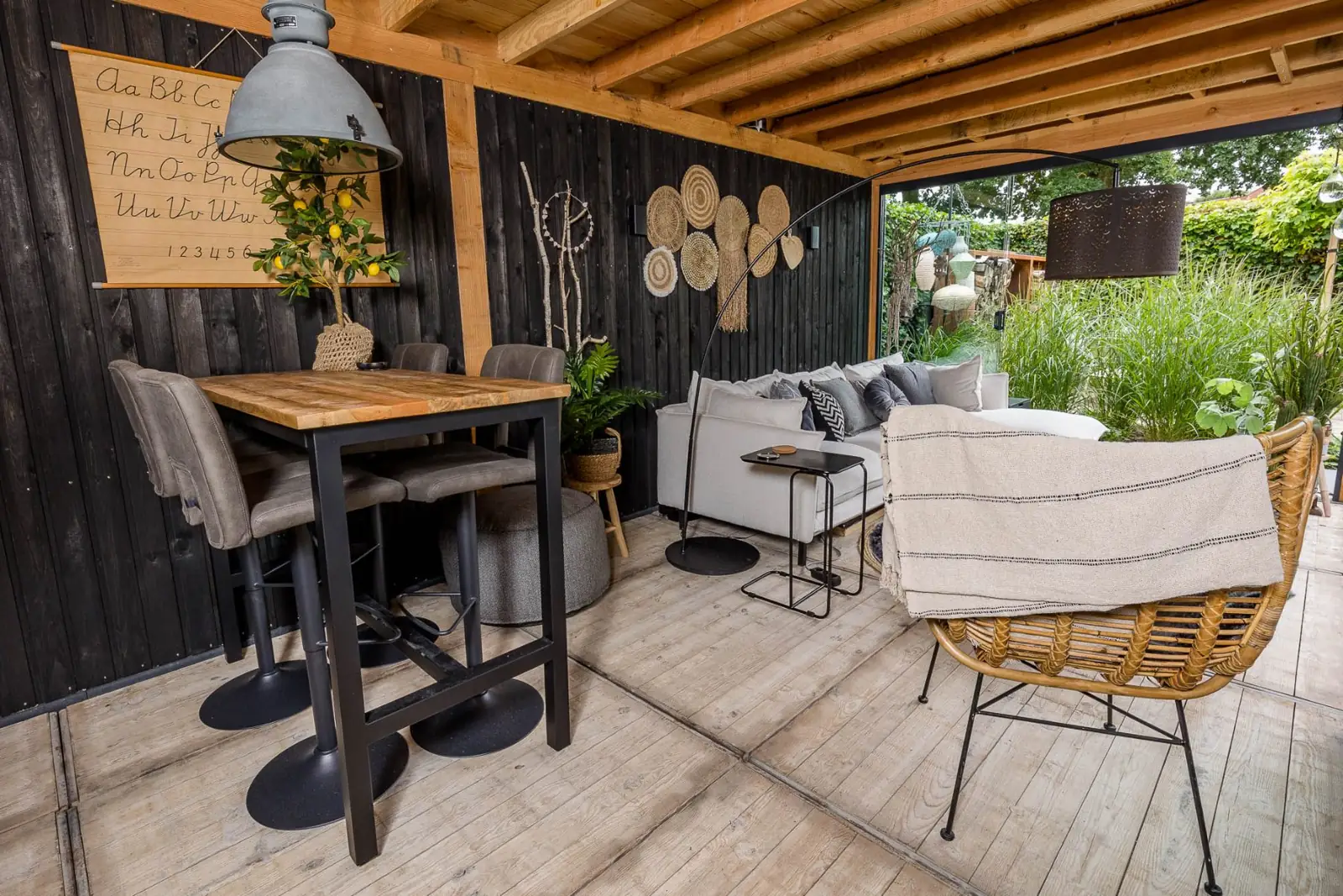 Bartafel en loungebank onder de houten overkapping met zwarte wand in Dalfsen