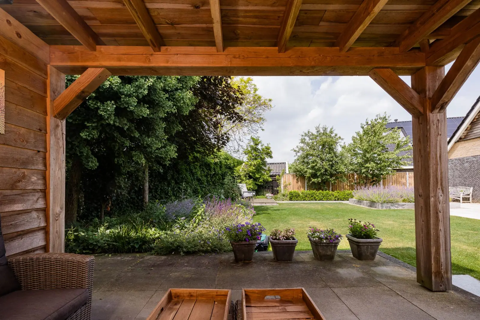 Zicht vanuit de houten overkapping over de border en het gazon in Hardenberg