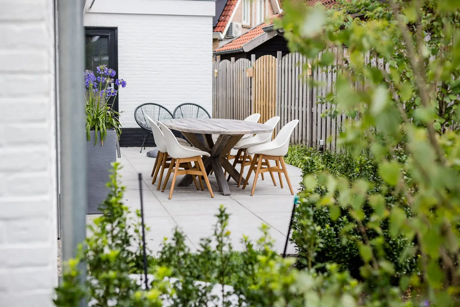Terras met eettafel en agapanthus in een hoge pot aan de witte gevel