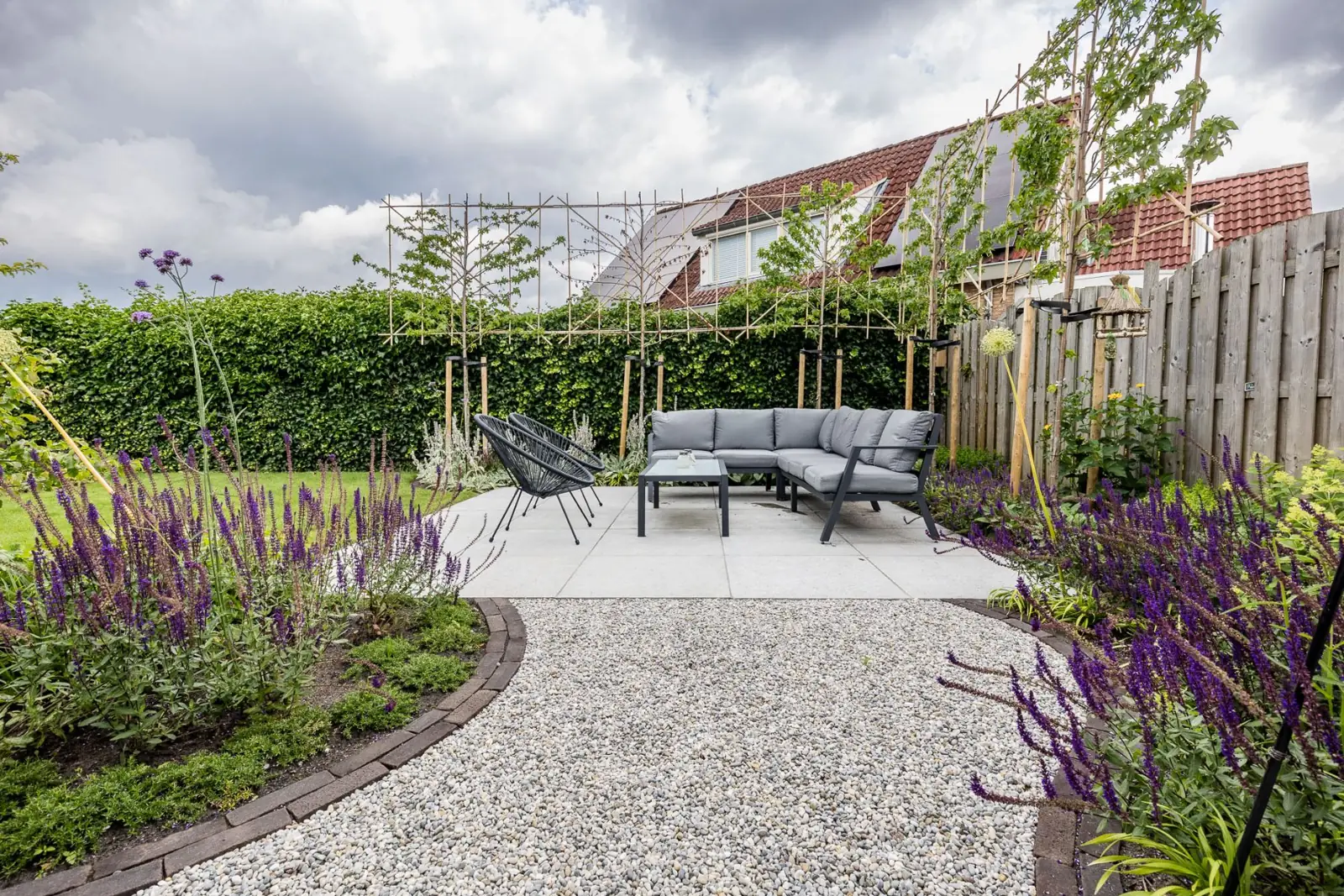 Grindpad met klinkerrand tussen borders met salie naar de loungeplek