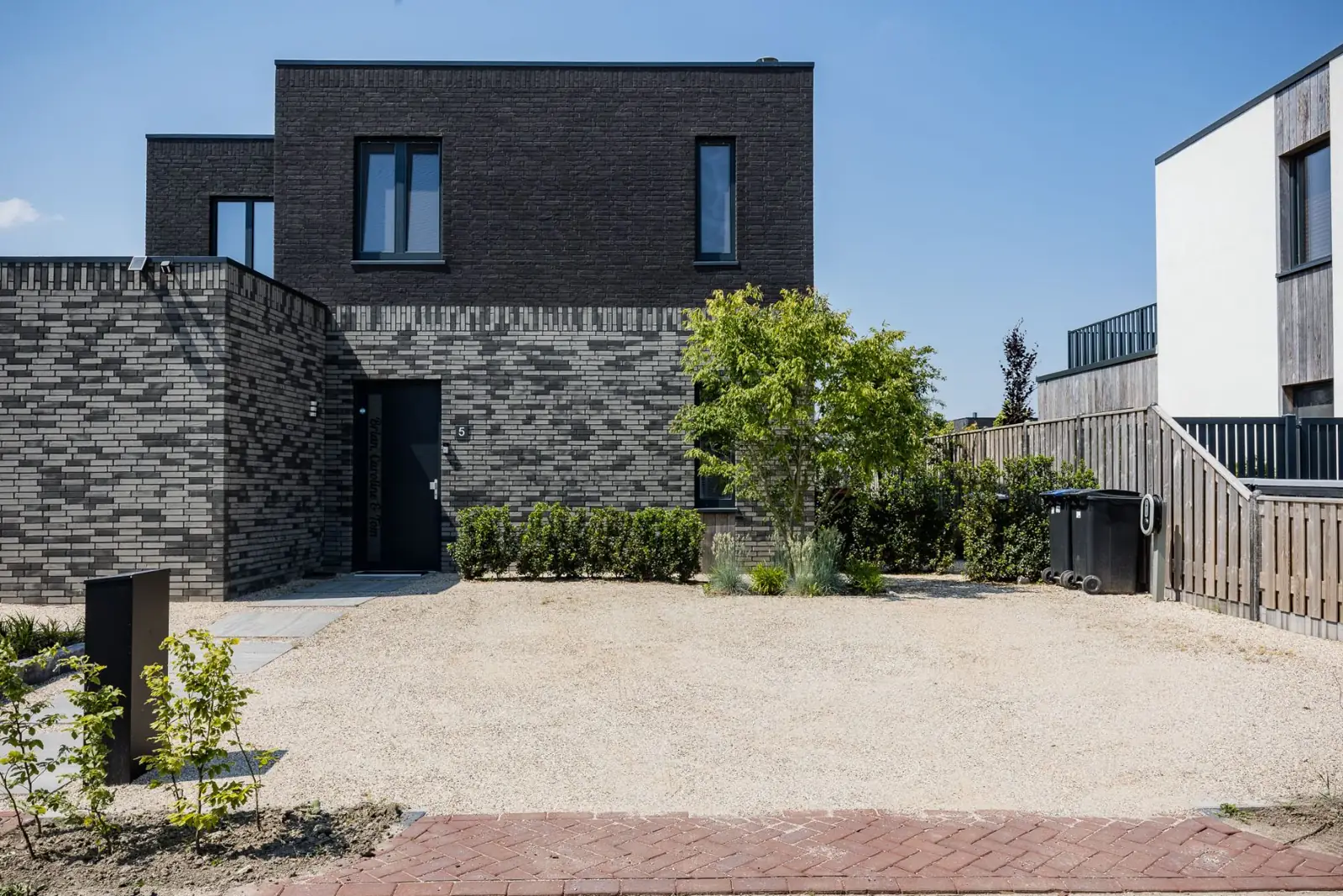 Voortuin van grind met hagen en een meerstammige boom voor de woning in Almere