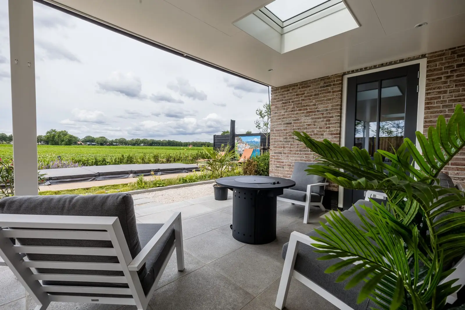 Loungehoek met vuurtafel onder de overkapping met zicht op de jacuzzi in Hardenberg